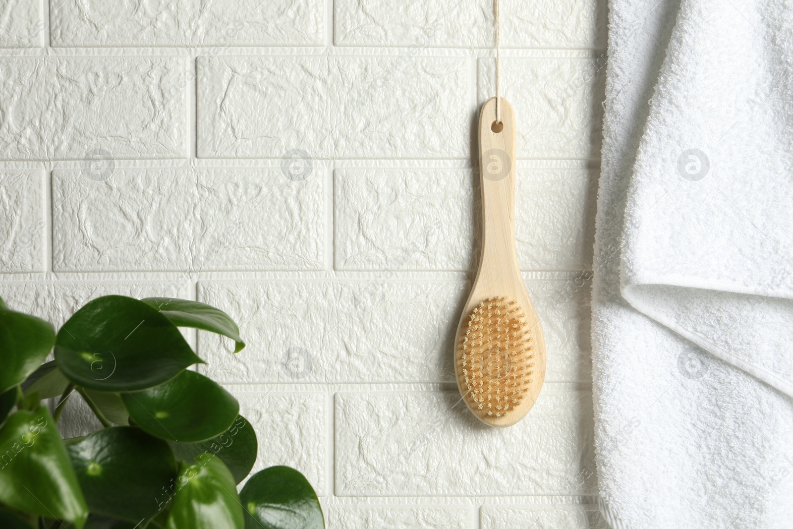 Photo of Bath accessories. Bamboo brush and terry towel on white brick wall