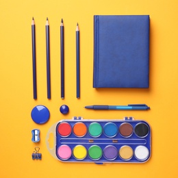 Different stationery on orange background, flat lay