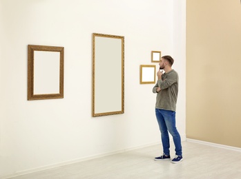 Young man viewing exposition in modern art gallery