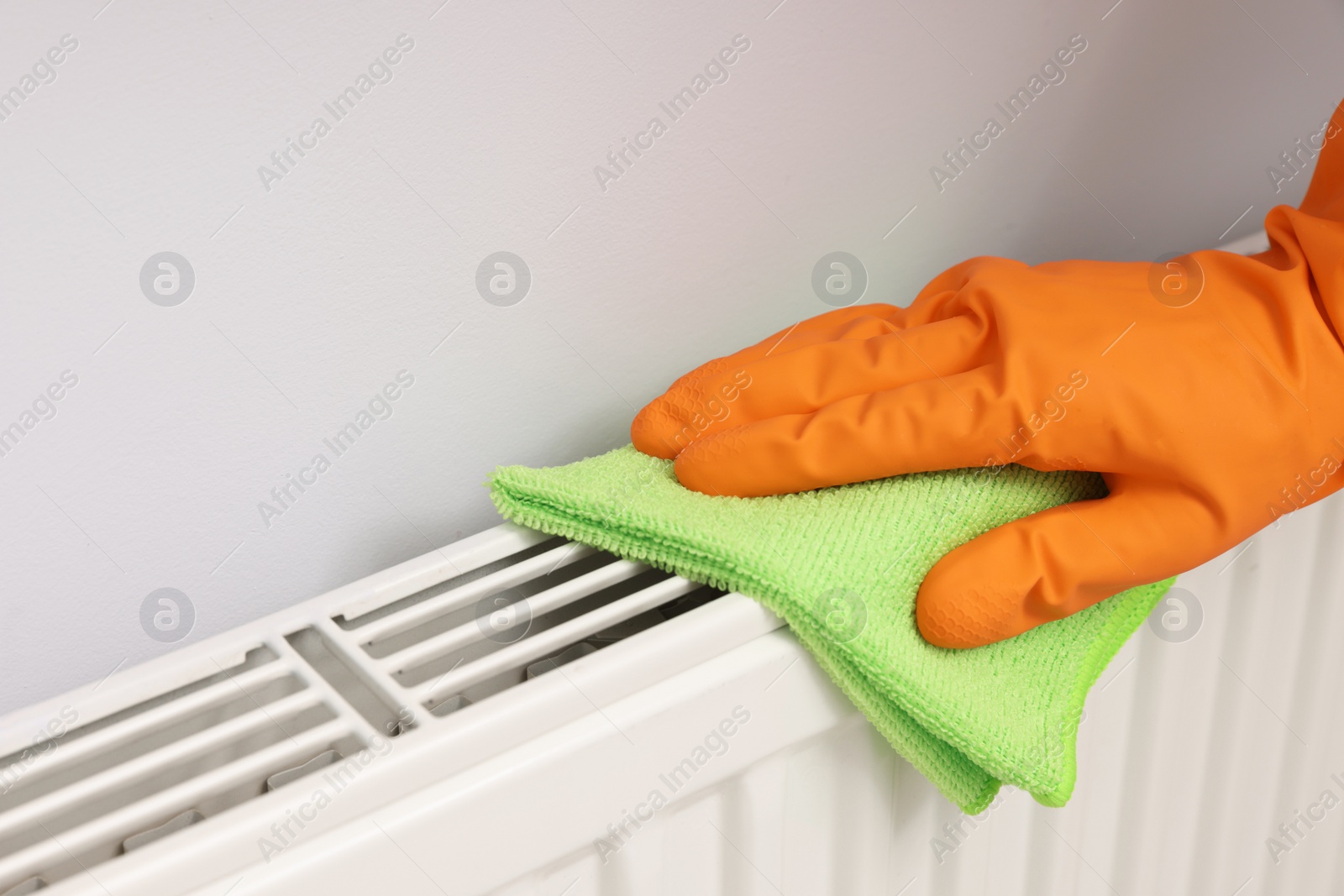 Photo of Woman cleaning radiator with rag indoors, closeup. Space for text