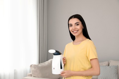 Photo of Happy woman with steam iron at home. Space for text