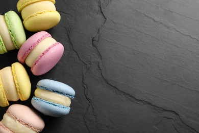 Delicious colorful macarons on black table, flat lay. Space for text