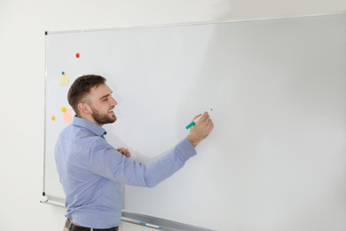 Photo of Portrait of young teacher writing on whiteboard in classroom