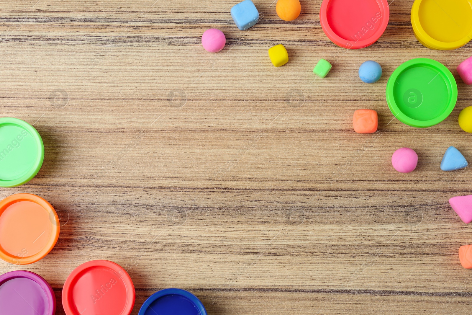 Photo of Different color play dough with plastic containers on wooden table, flat lay. Space for text