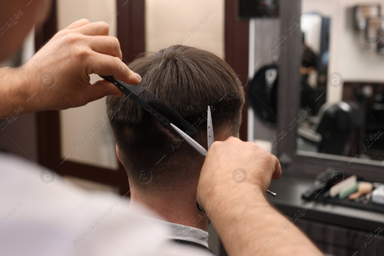 Photo of Professional hairdresser cutting man's hair in barbershop