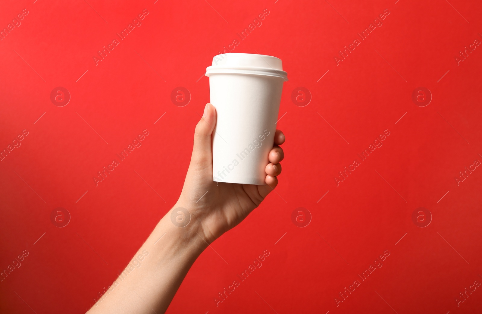 Photo of Woman holding takeaway paper coffee cup on red background, closeup