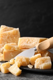 Parmesan cheese with board and knife on grey table, closeup