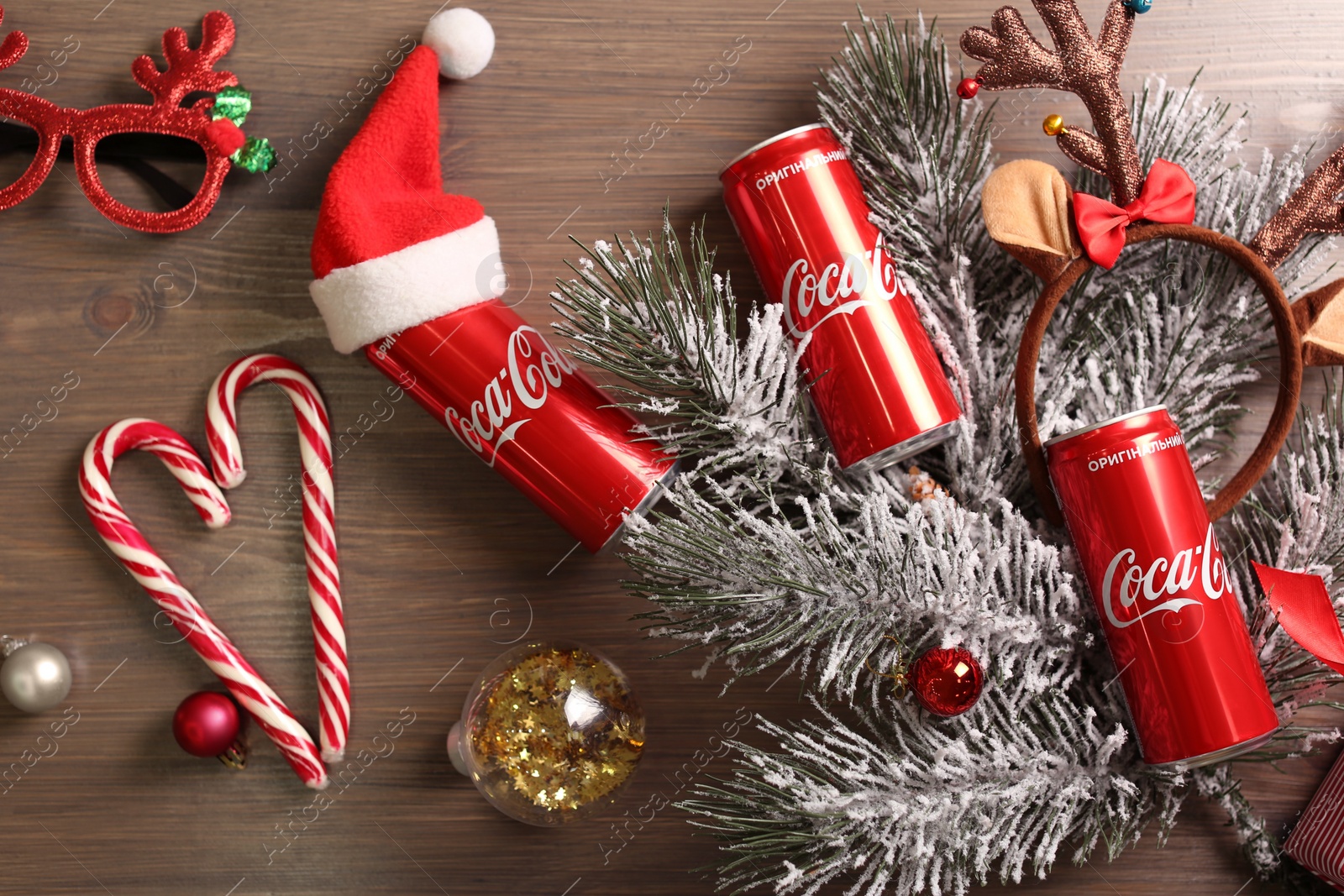 Photo of MYKOLAIV, UKRAINE - January 01, 2021: Flat lay composition with Coca-Cola cans and Christmas decorations on wooden background