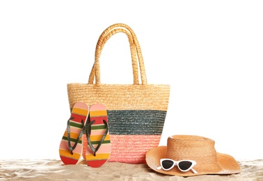 Photo of Wicker bag and beach accessories on sand against white background