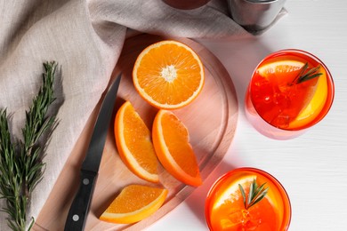 Aperol spritz cocktail, rosemary and orange slices on white table, flat lay