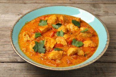 Photo of Delicious chicken curry on wooden table, closeup