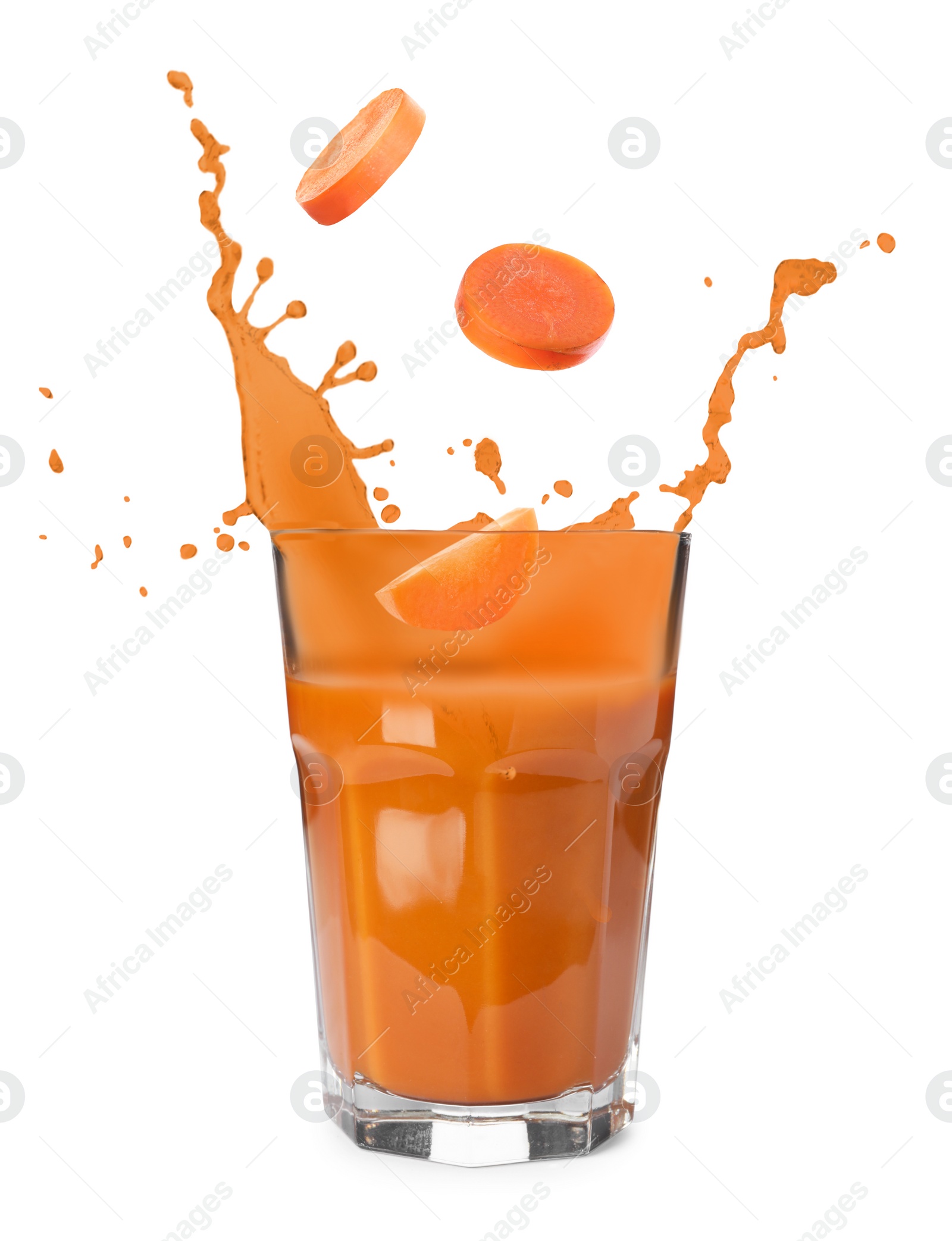 Image of Carrot slices falling into glass of fresh juice with splashes on white background