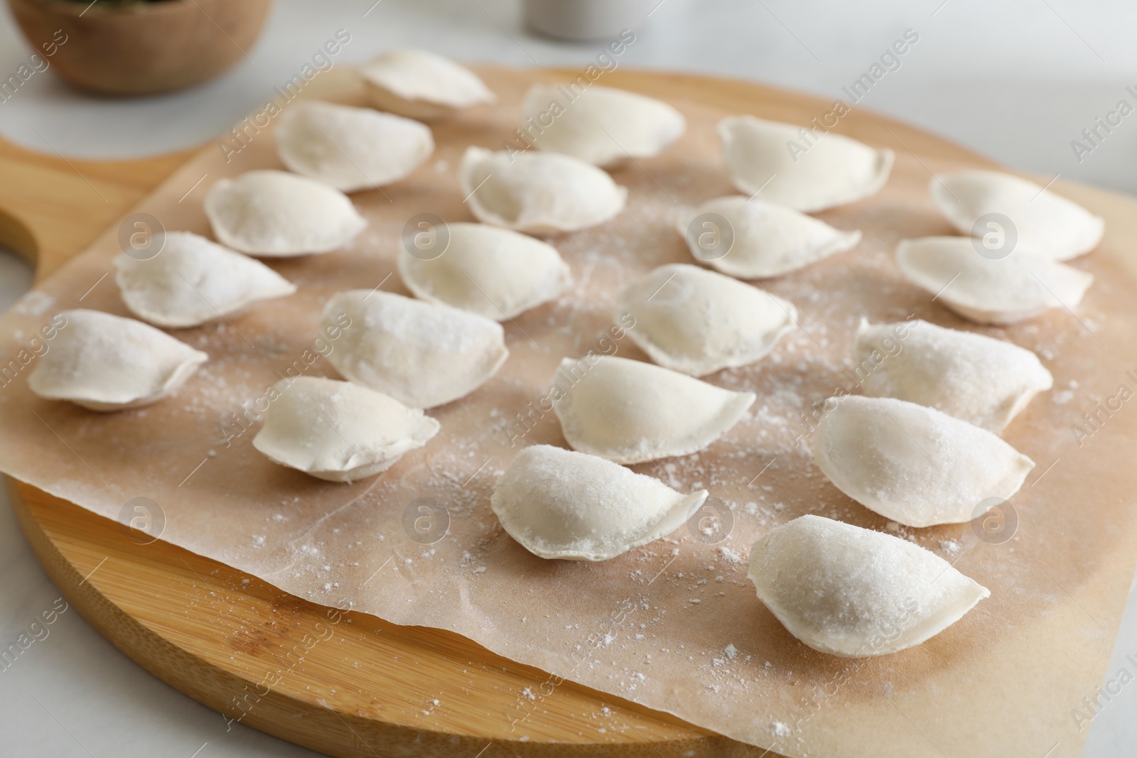 Photo of Fresh uncooked dumplings on white table, closeup