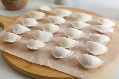 Photo of Fresh uncooked dumplings on white table, closeup