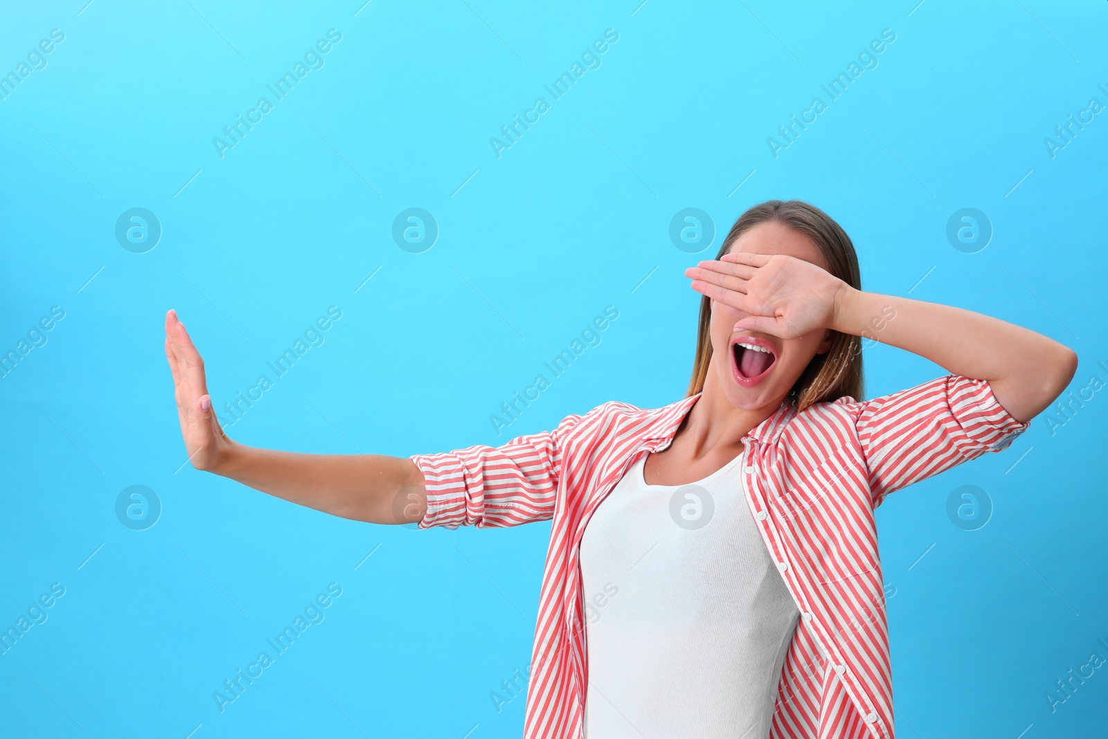 Photo of Young woman covering eyes with hands on blue background