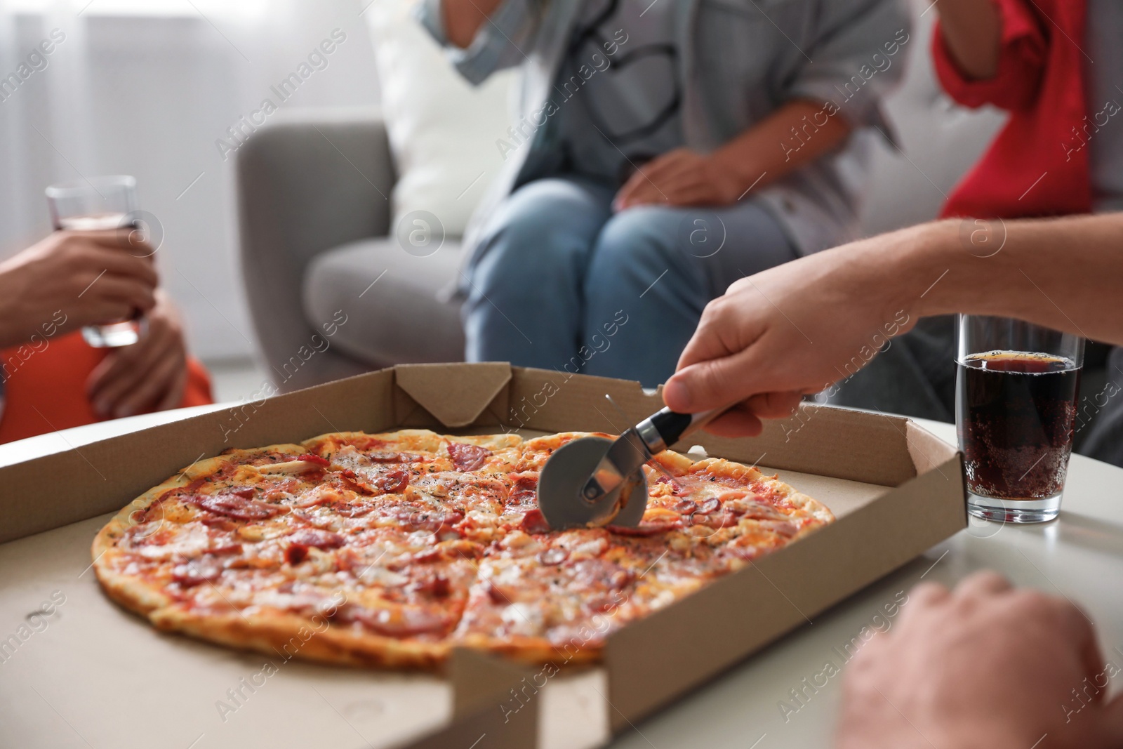 Photo of Man cutting fresh pizza on table, closeup