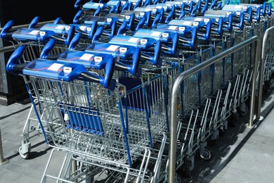 Many empty shopping carts near supermarket, closeup