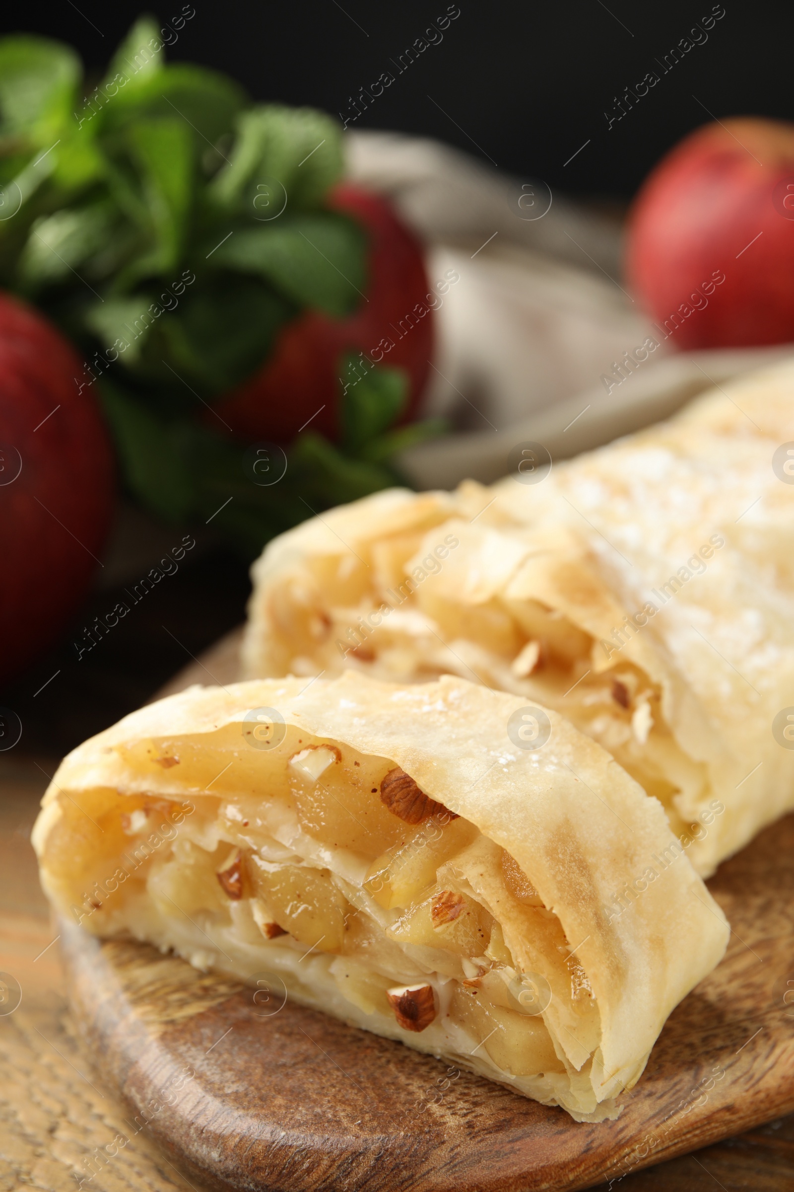 Photo of Delicious apple strudel with almonds on wooden table, closeup