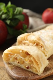 Photo of Delicious apple strudel with almonds on wooden table, closeup