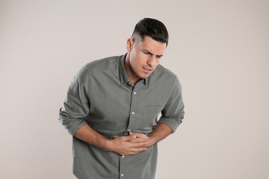 Photo of Man suffering from stomach ache on beige background. Food poisoning