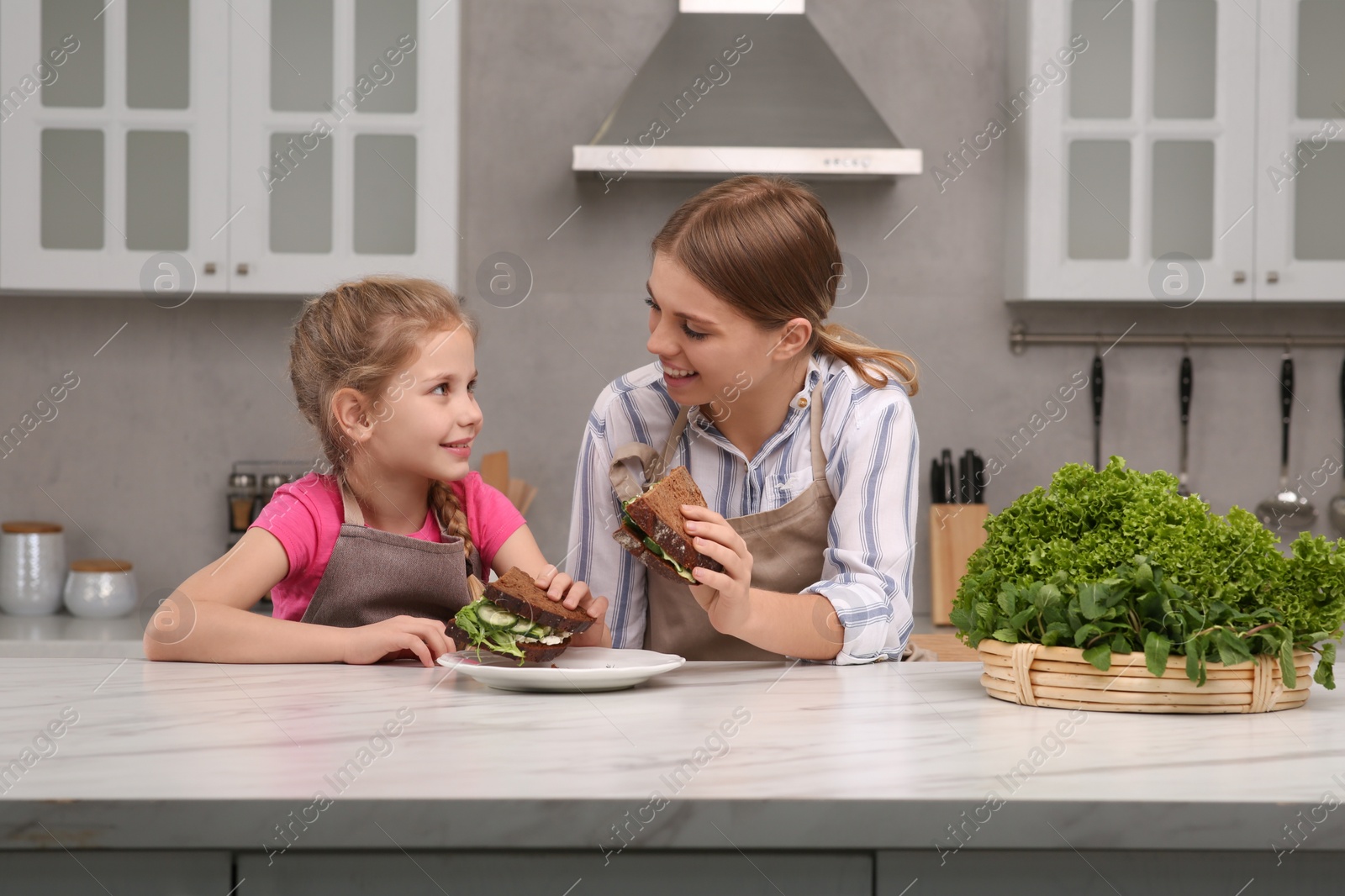 Photo of Little daughter with her mom having breakfast together in kitchen. Happy Mother's Day