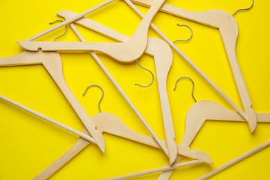 Photo of Empty wooden hangers on yellow background, flat lay