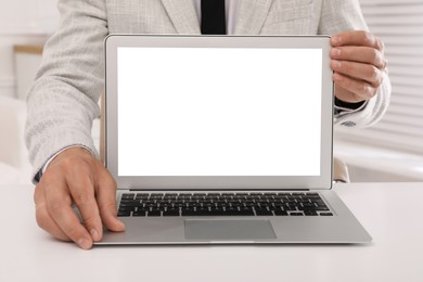 Photo of Businessman with modern laptop at white table indoors, closeup. Space for design