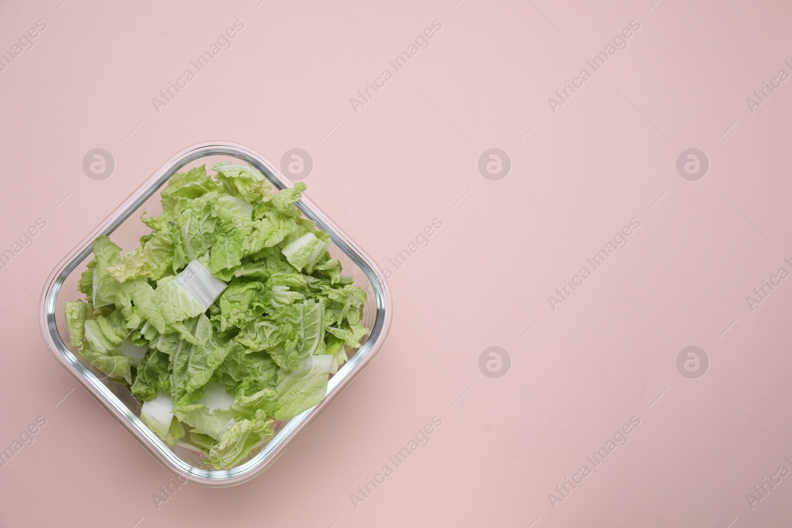 Photo of Glass container with fresh cabbage on light pink background, top view. Space for text