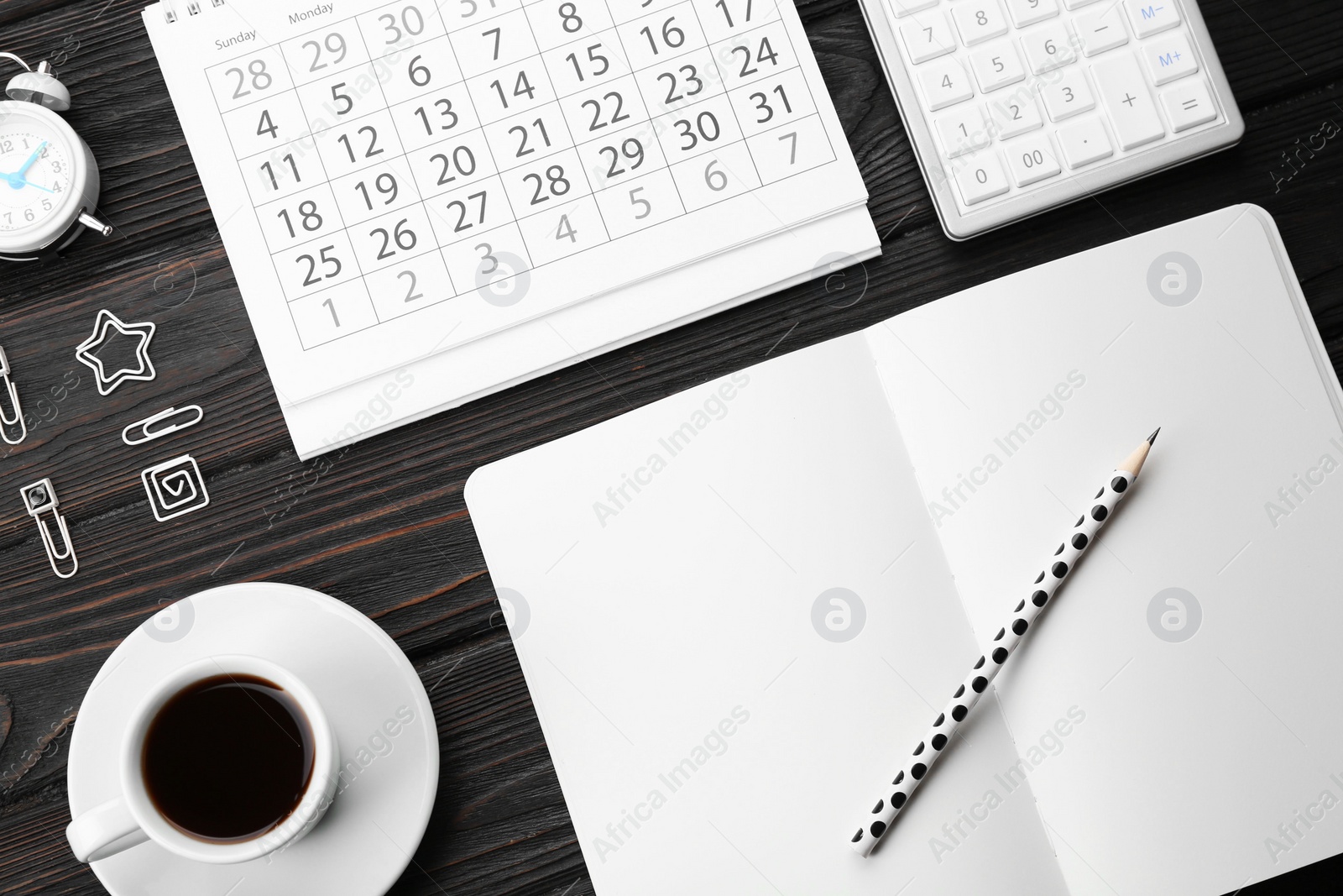 Photo of Flat lay composition with calendar and cup of coffee on black wooden table