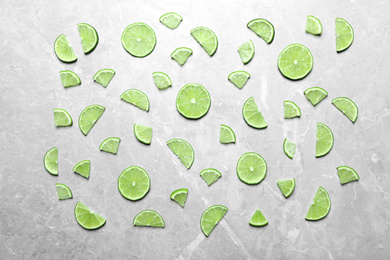 Photo of Slices of fresh juicy lime on marble table, flat lay