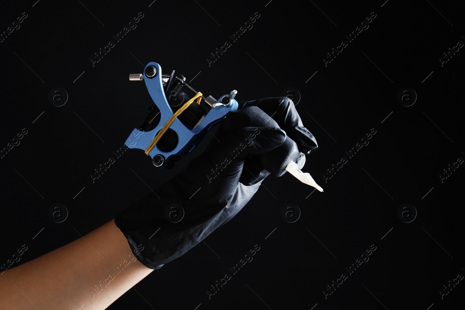 Photo of Professional tattoo artist with machine on black background, closeup. Space for text