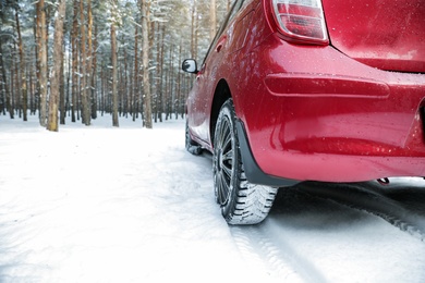 Photo of Modern car on snowy road in winter forest, closeup. Space for text
