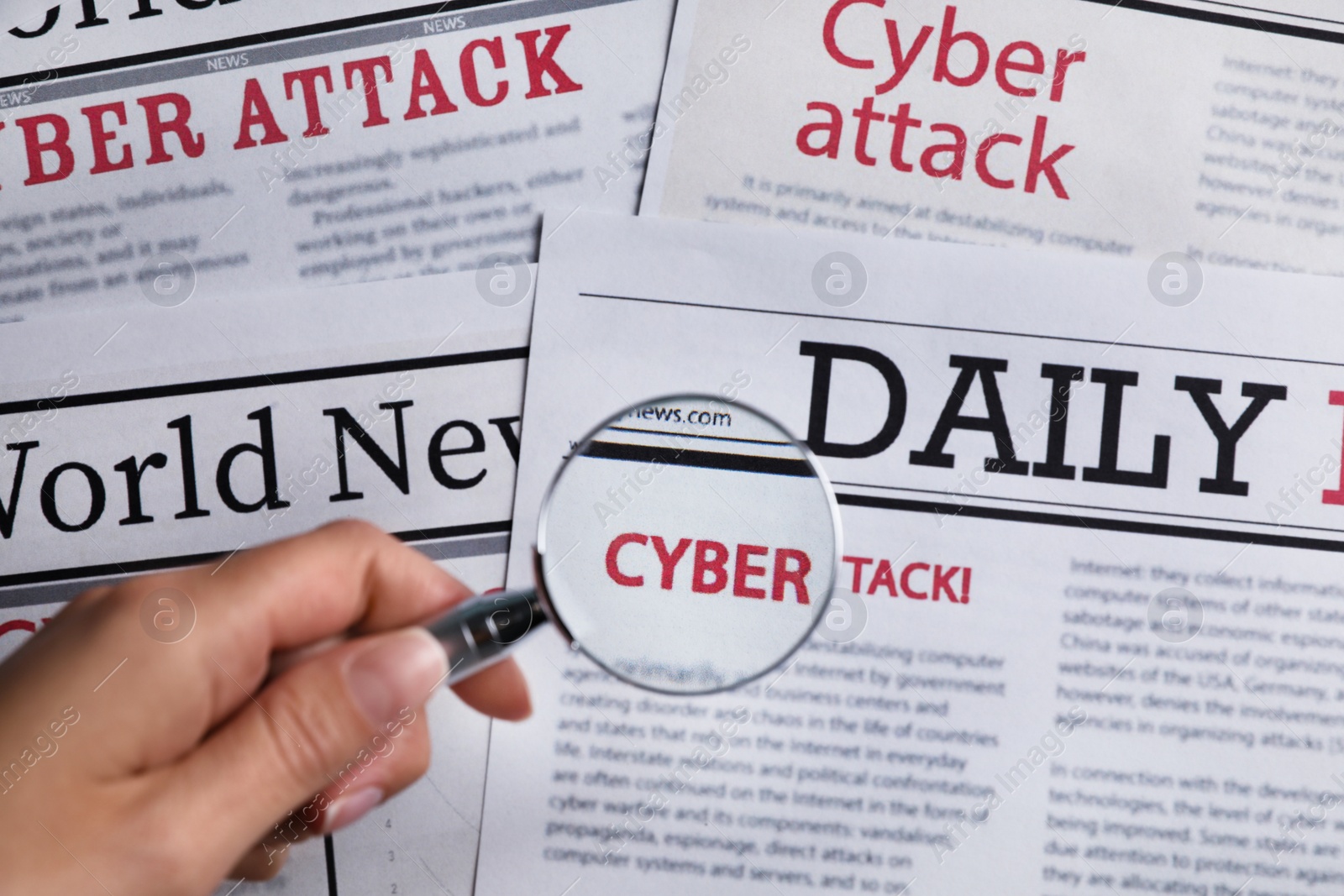 Photo of Woman using magnifying glass to read newspaper with headline CYBER ATTACK, top view