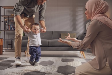 Happy Muslim family with little son in living room