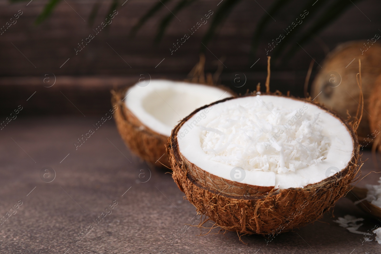 Photo of Coconut pieces in nut shell on brown table, space for text