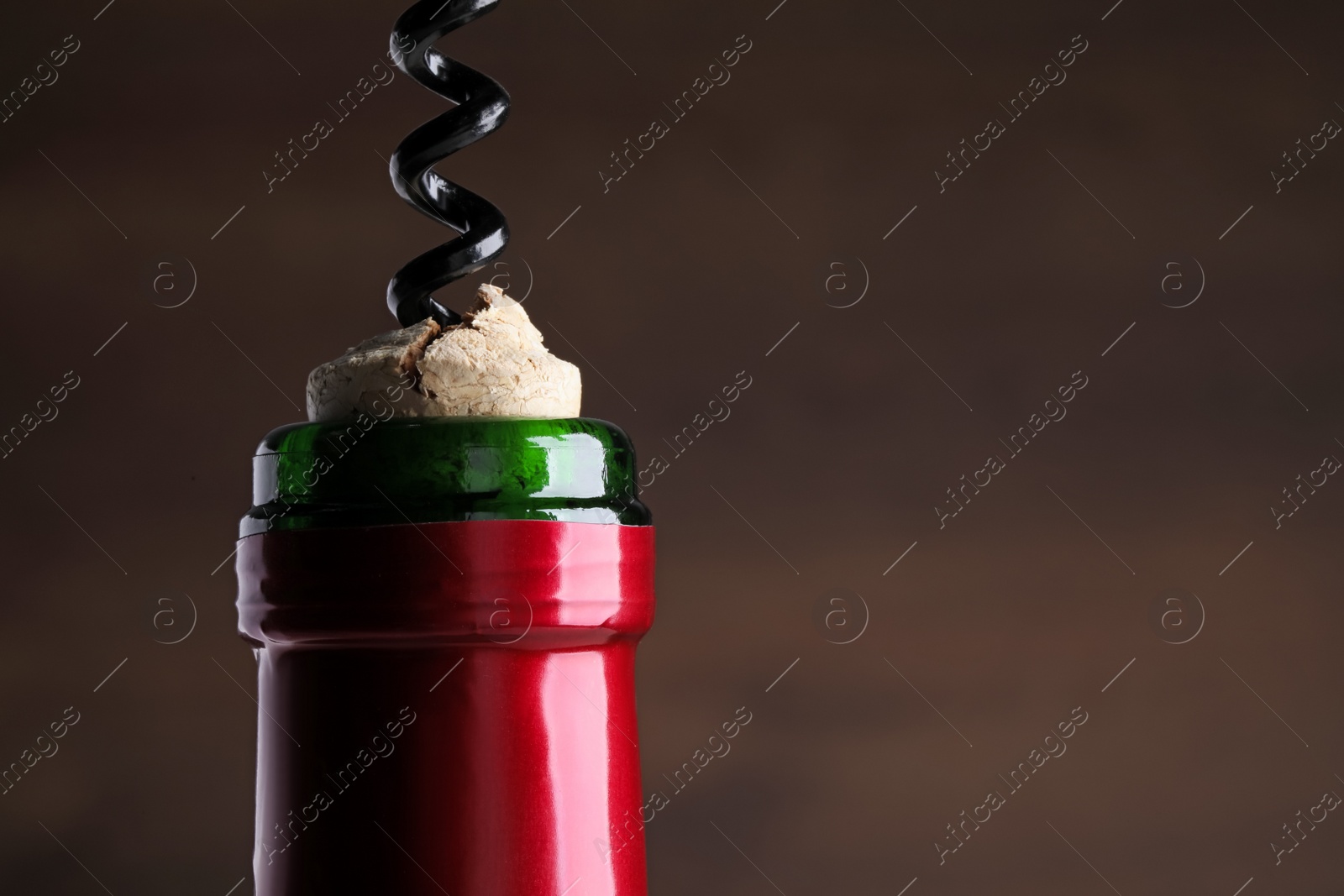 Photo of Opening wine bottle with corkscrew on dark background, closeup. Space for text