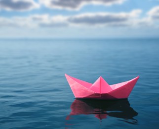 Image of Pink paper boat floating on calm sea 