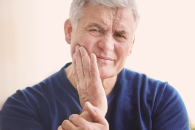 Photo of Mature man suffering from toothache at home