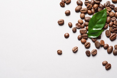 Fresh green coffee leaves and beans on light background, flat lay. Space for text