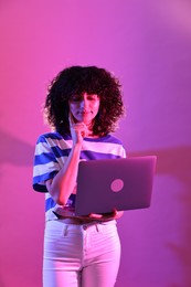 Photo of Beautiful young woman with laptop on color background in neon lights