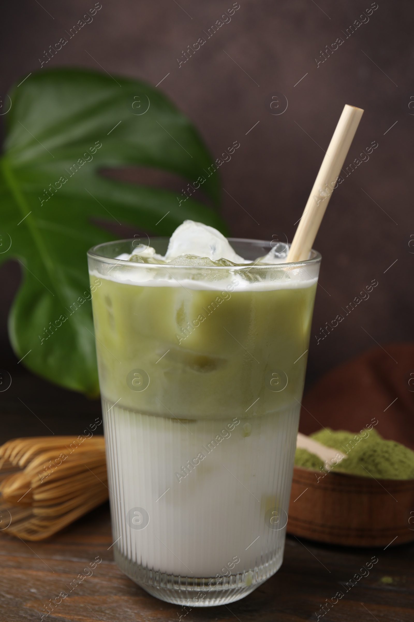 Photo of Glass of tasty iced matcha latte on wooden table