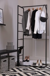 Rack with stylish women's clothes and bench in dressing room