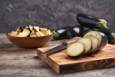 Photo of Wooden board with cut eggplant on table