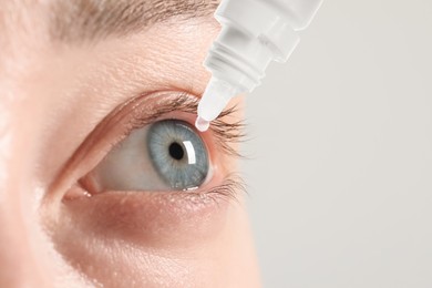Woman applying eye drops on light background, closeup. Space for text