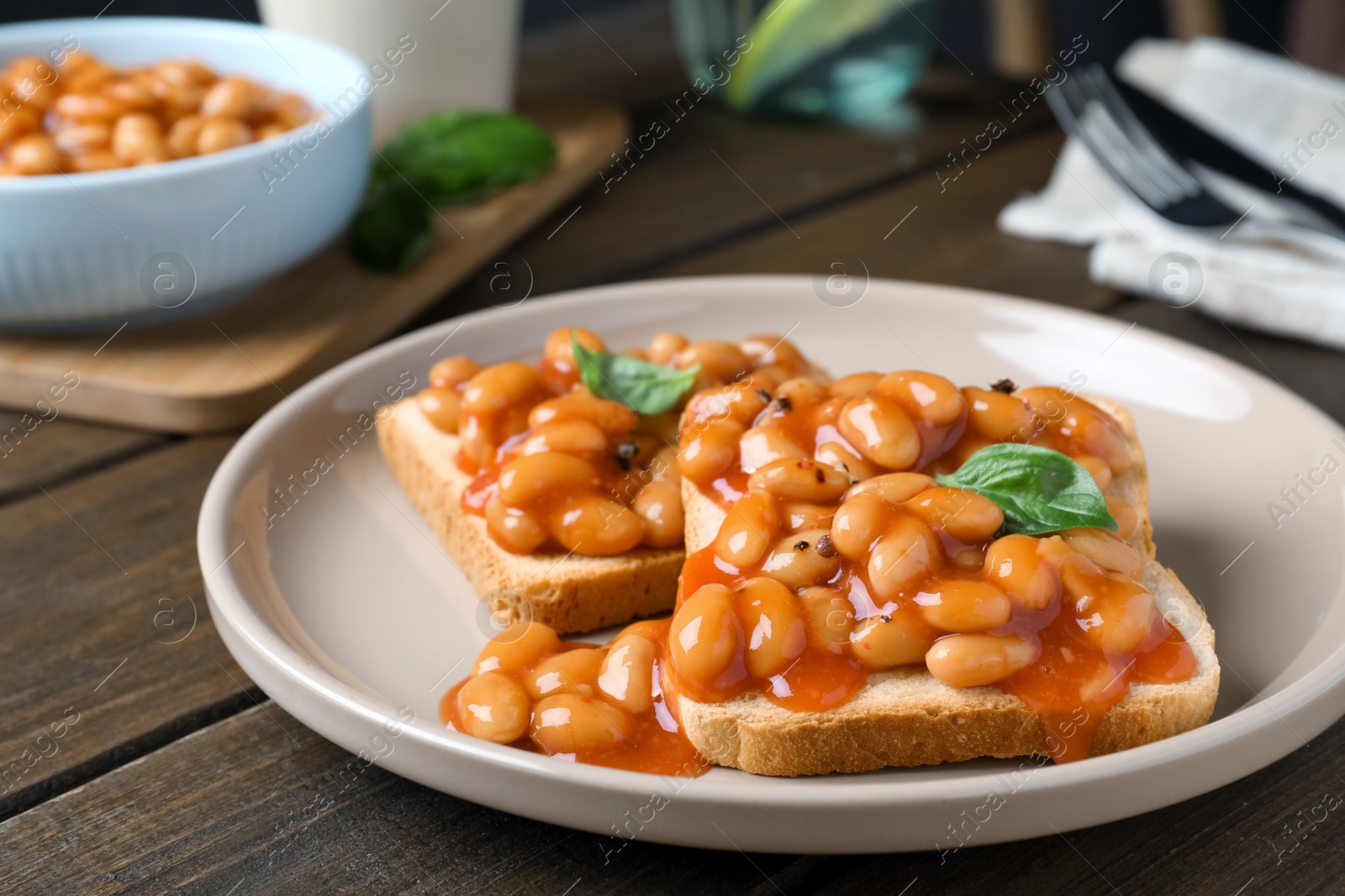 Photo of Toasts with delicious canned beans on wooden table, closeup