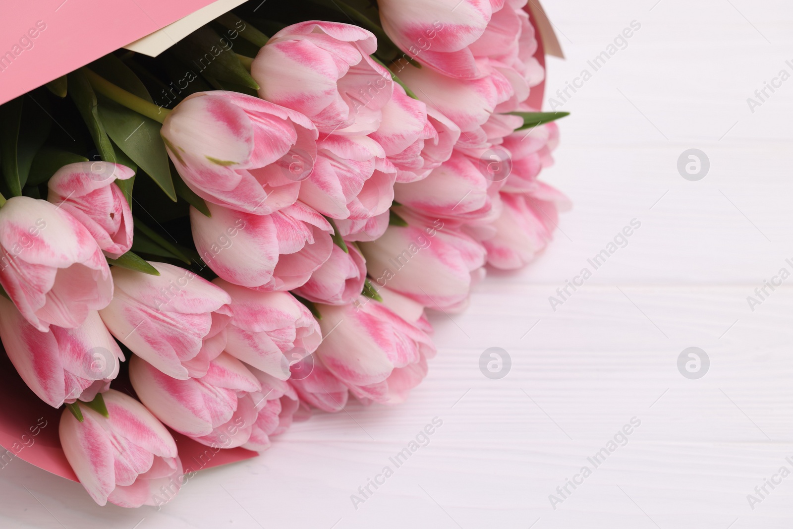 Photo of Beautiful bouquet of fresh pink tulips on white wooden table, closeup. Space for text