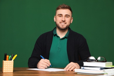 Photo of Portrait of young teacher at table against green background