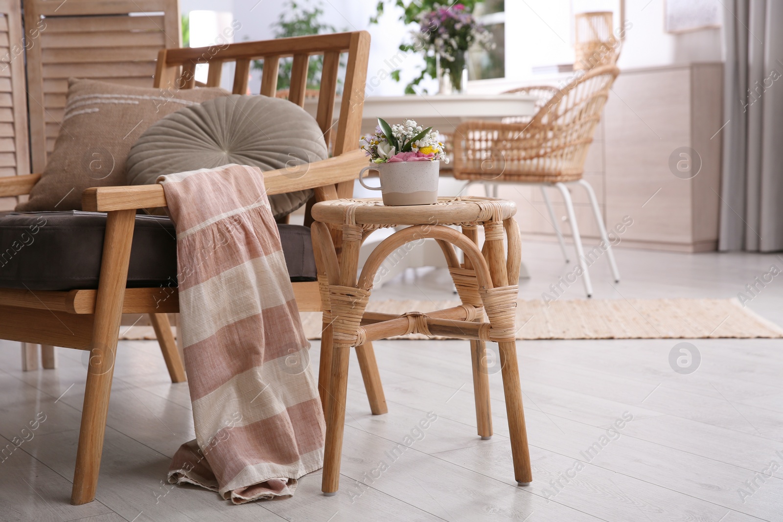 Photo of Stylish wooden stool with bouquet of flowers near armchair in room. Interior element