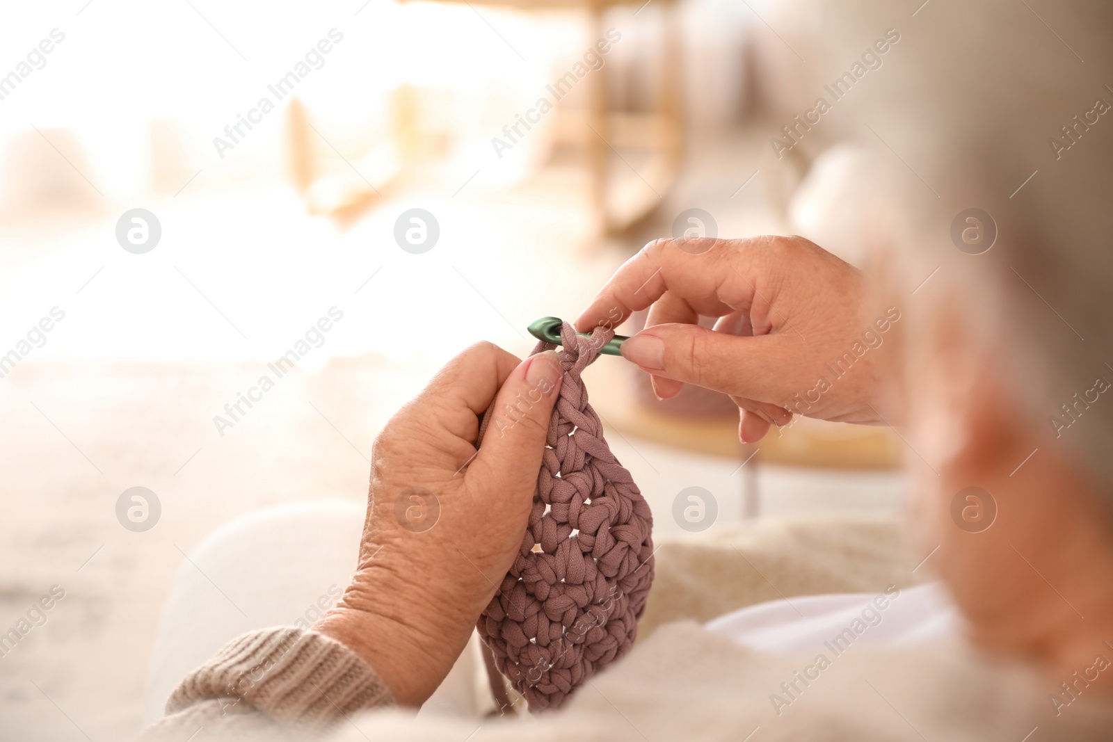 Photo of Elderly woman crocheting at home, closeup. Creative hobby