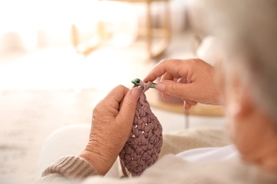 Elderly woman crocheting at home, closeup. Creative hobby